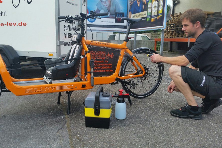 Mitarbeiter reinigt ein Lastenrad mit Niederdruck